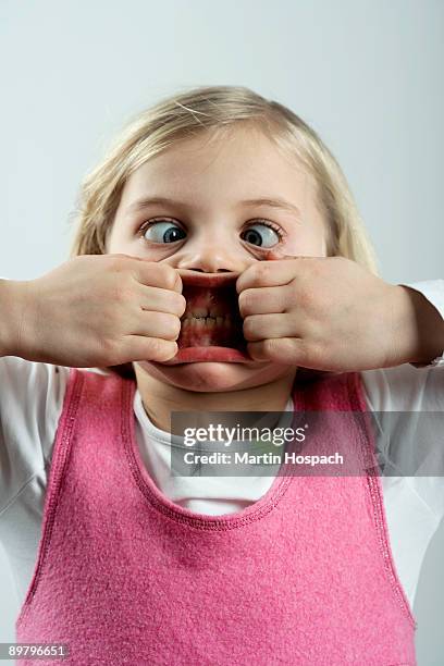a little girl making a scary face - finger in mouth stockfoto's en -beelden