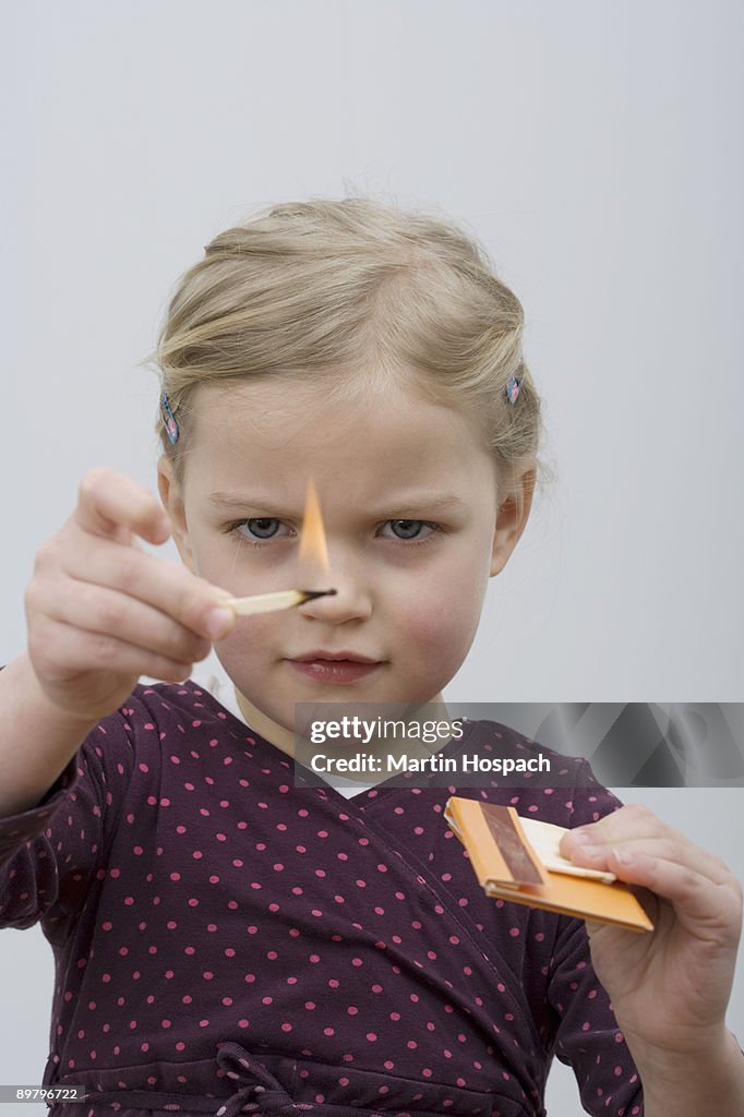 A young girl playing with matches