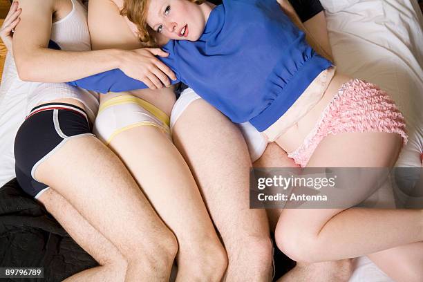 a young woman lying across three men on a bed - pin up stock-fotos und bilder