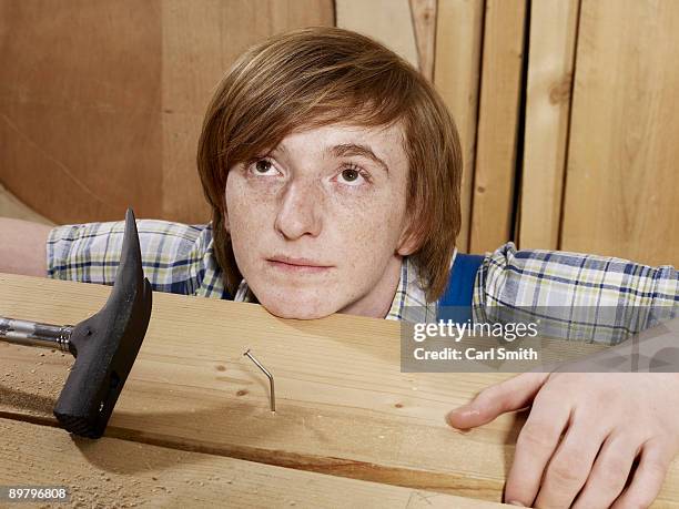 a young man behind a bent nail in wood - tordu photos et images de collection