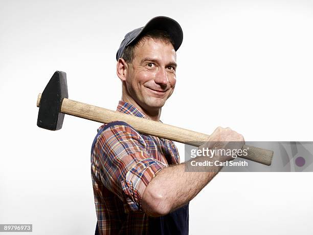 a man holding a sledgehammer over his shoulder - sledge hammer stock pictures, royalty-free photos & images