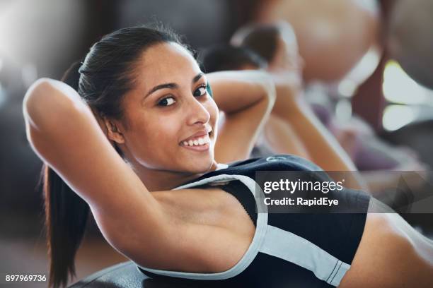 smiling young woman doing sit-ups at health club - armpit stock pictures, royalty-free photos & images