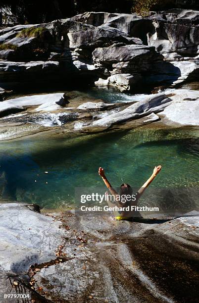 a woman sliding down rocks into a pool of water, piedmont, italy - marisma fotografías e imágenes de stock