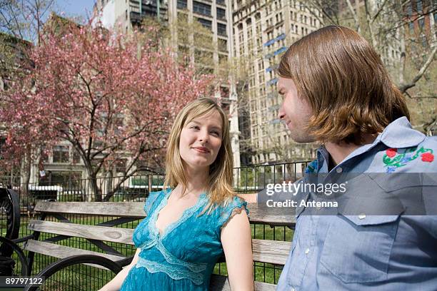 a young couple sitting on a park bench together, central park, new york city - couple central park stockfoto's en -beelden