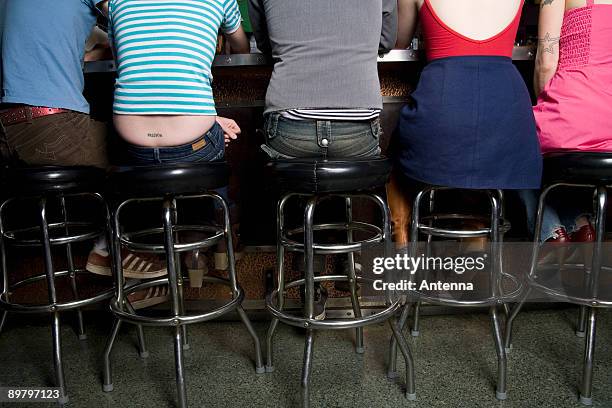 rear view of a row of friends sitting at a bar counter - tabouret photos et images de collection