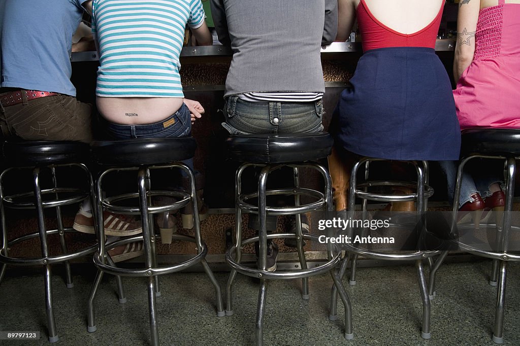 Rear view of a row of friends sitting at a bar counter