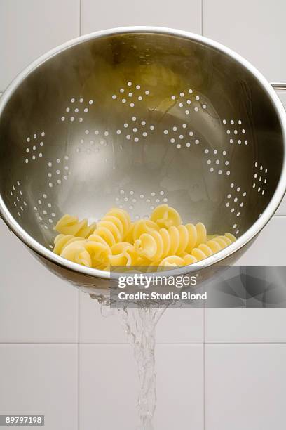 water draining from a colander of fusilli pasta - colander stock pictures, royalty-free photos & images