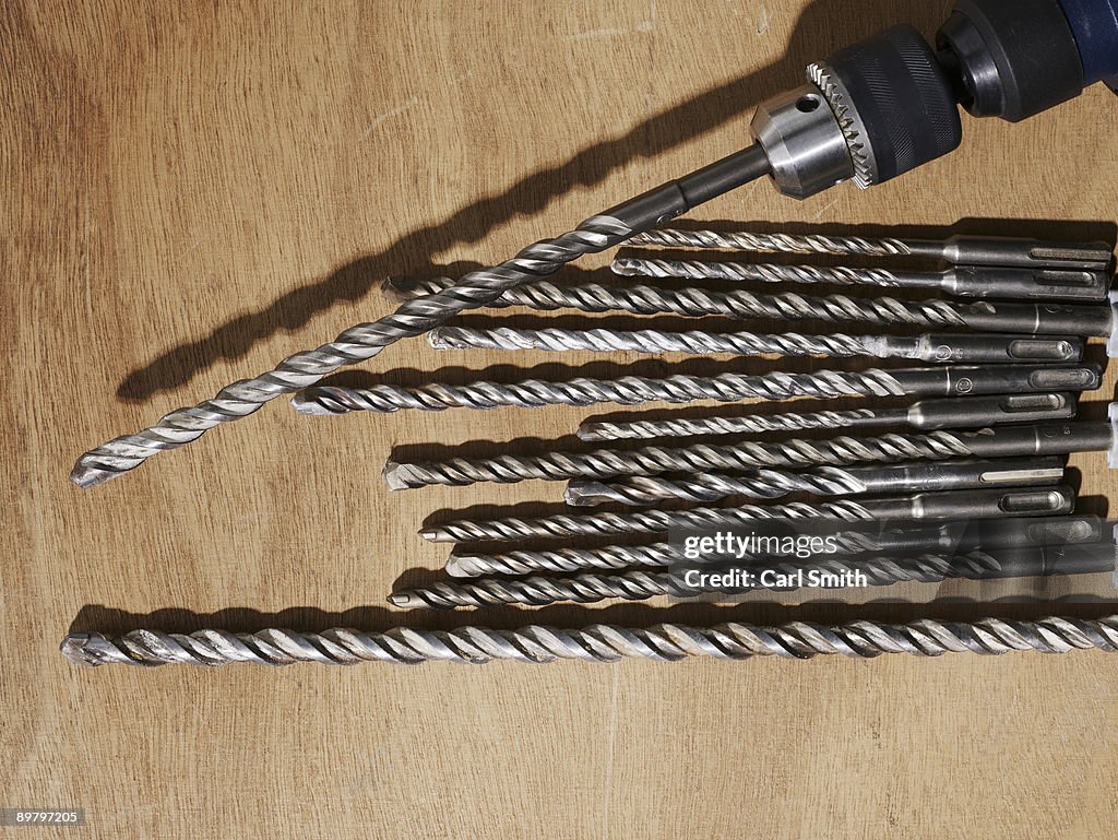 A drill and assorted drill bits on a bench