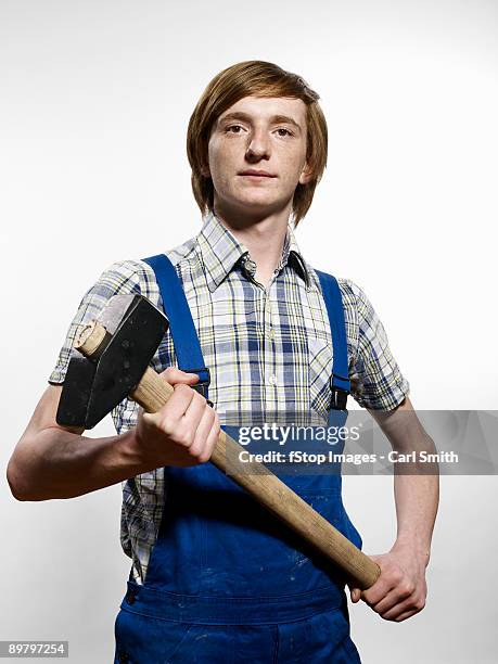 a young man holding a sledgehammer - martillo herramienta de mano fotografías e imágenes de stock