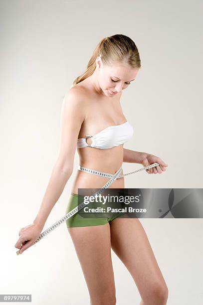 woman measuring her waist with a tape measure - strapless stock pictures, royalty-free photos & images