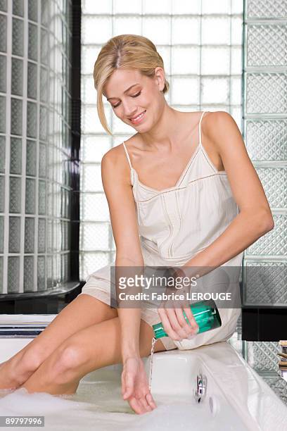 woman pouring liquid soap in a bathtub - bubble bath bottle stock pictures, royalty-free photos & images