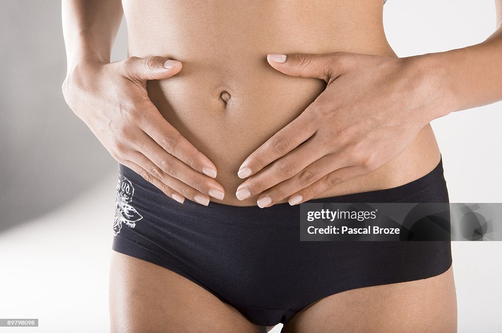 Mid section view of a woman touching her abdomen