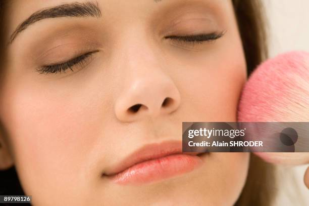 woman applying blusher on her face - woman applying blush stock pictures, royalty-free photos & images