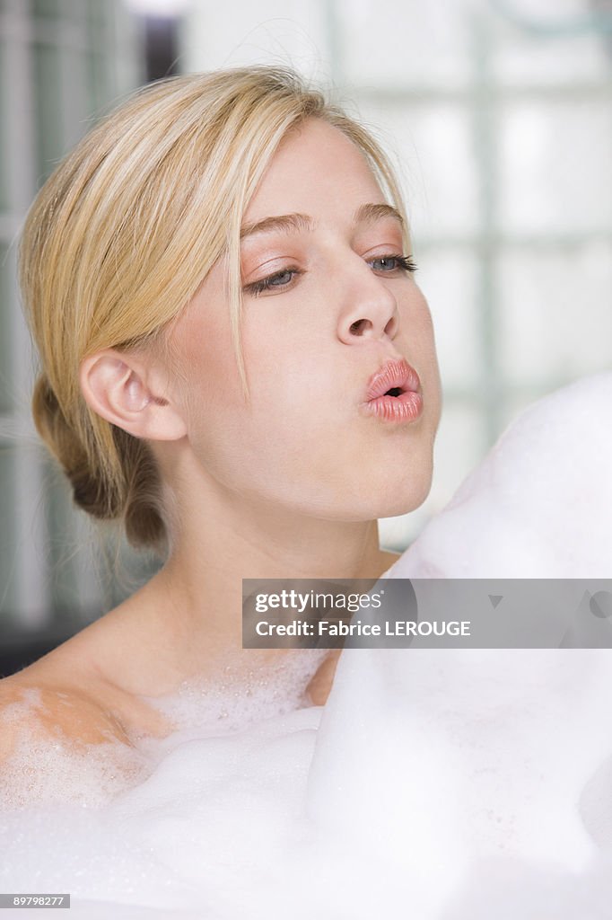 Woman blowing bubbles in a bathtub