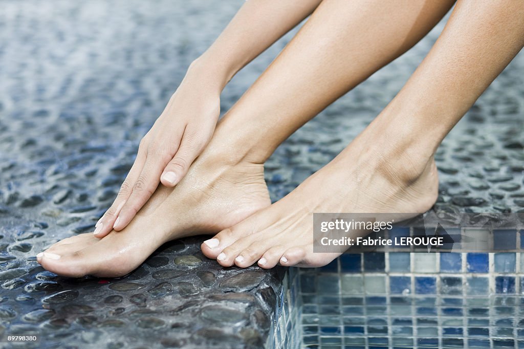 Woman rubbing her foot at the poolside