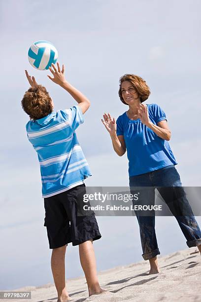 woman with her grandson playing beach volleyball - male throwing water polo ball stockfoto's en -beelden