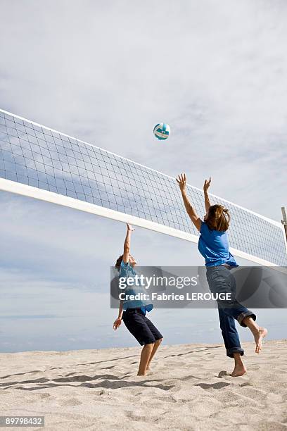 woman with her grandson playing beach volleyball - wurf oder sprungdisziplin damen stock-fotos und bilder