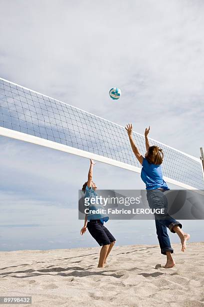 woman with her grandson playing beach volleyball - male throwing water polo ball stockfoto's en -beelden