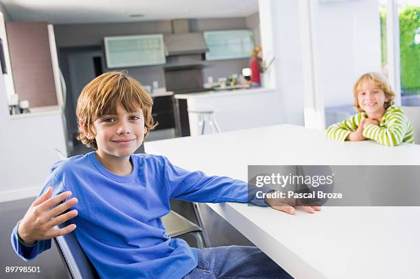 two boys sitting at a dining table - sitting at table looking at camera stock pictures, royalty-free photos & images