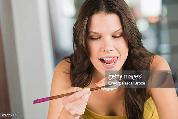 close-up of a woman eating sushi - mensentong stockfoto's en -beelden