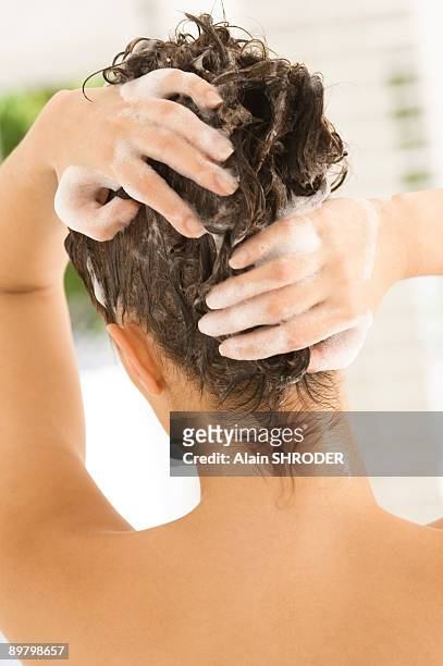 rear view of a woman shampooing her hair - se laver les cheveux photos et images de collection