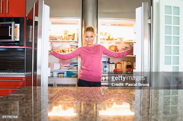 portrait of a woman standing in front of a refrigerator - tidy room stock pictures, royalty-free photos & images