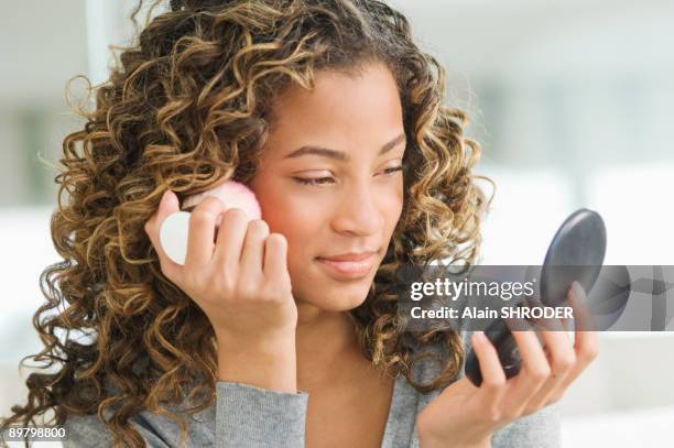 girl applying make-up on her face - puderdose stock-fotos und bilder