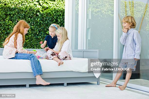 three girls playing with toys and a boy looking at them - barefoot redhead ストックフォトと画像