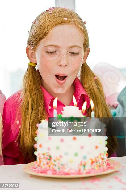girl blowing out candles on a birthday cake - codino foto e immagini stock