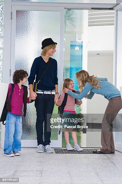 woman with her children and a nanny at the entrance of a house - nanny smiling stockfoto's en -beelden