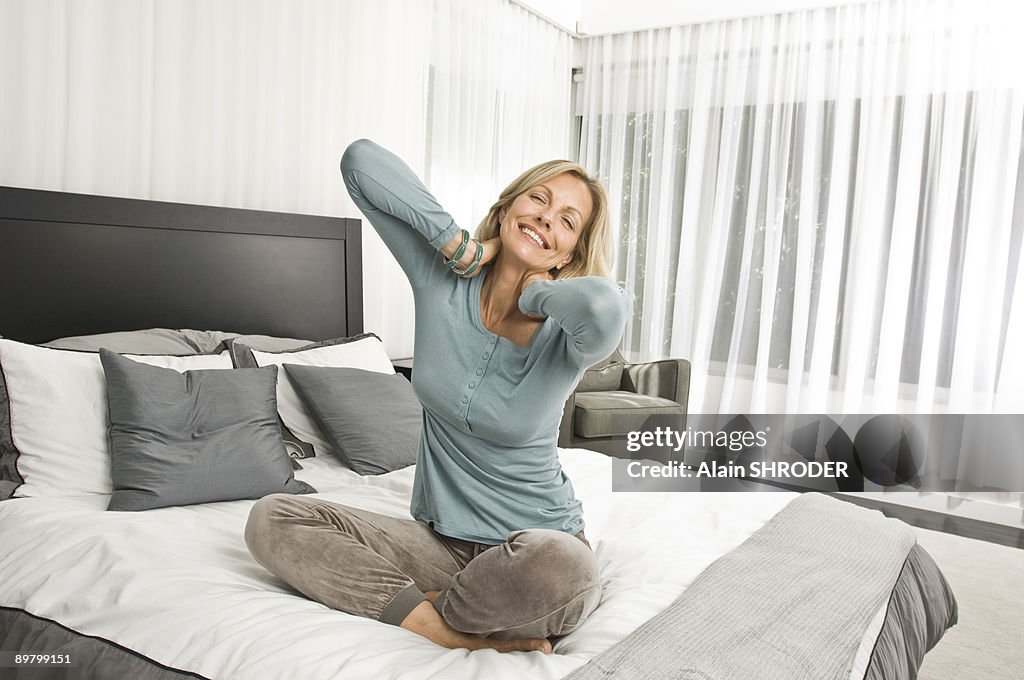 Woman stretching in bed and smiling