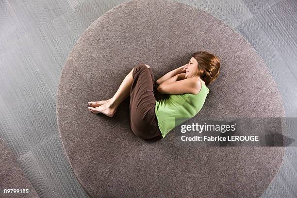 woman lying on a round sofa - woman curled up stock pictures, royalty-free photos & images