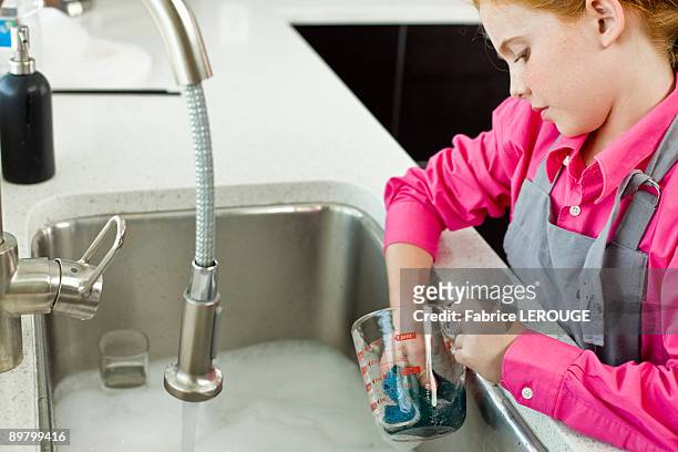 girl washing a measuring jug at a sink - water in measuring cup stock pictures, royalty-free photos & images
