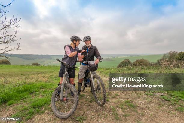 mature couple on mountain bikes checking directions - old howard fotografías e imágenes de stock