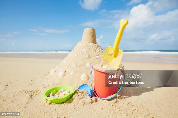 sandcastle with sand pail and shovel on the beach in france, europe - sandburg stock-fotos und bilder