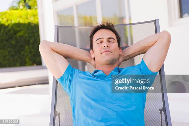 man sleeping on a lounge chair - zurücklehnen stock-fotos und bilder