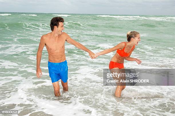 couple holding hands and walking in water on the beach - ankle deep in water fotografías e imágenes de stock
