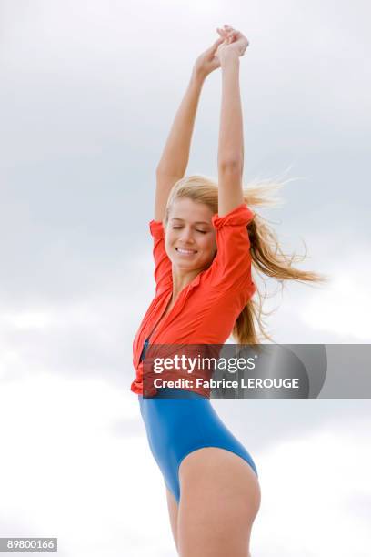 woman standing with her arms raised on the beach - swimming costume stock pictures, royalty-free photos & images