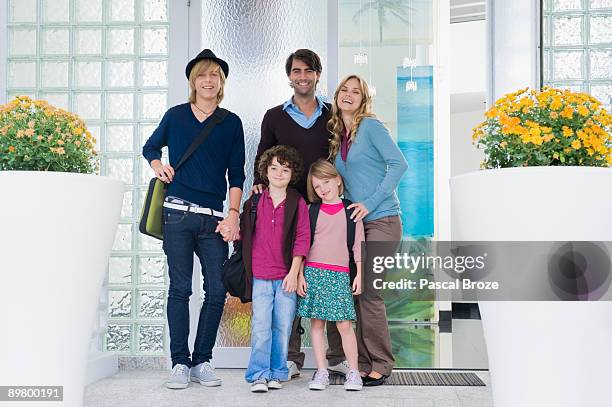 couple with their children and a nanny at the door of a house - nanny smiling stockfoto's en -beelden