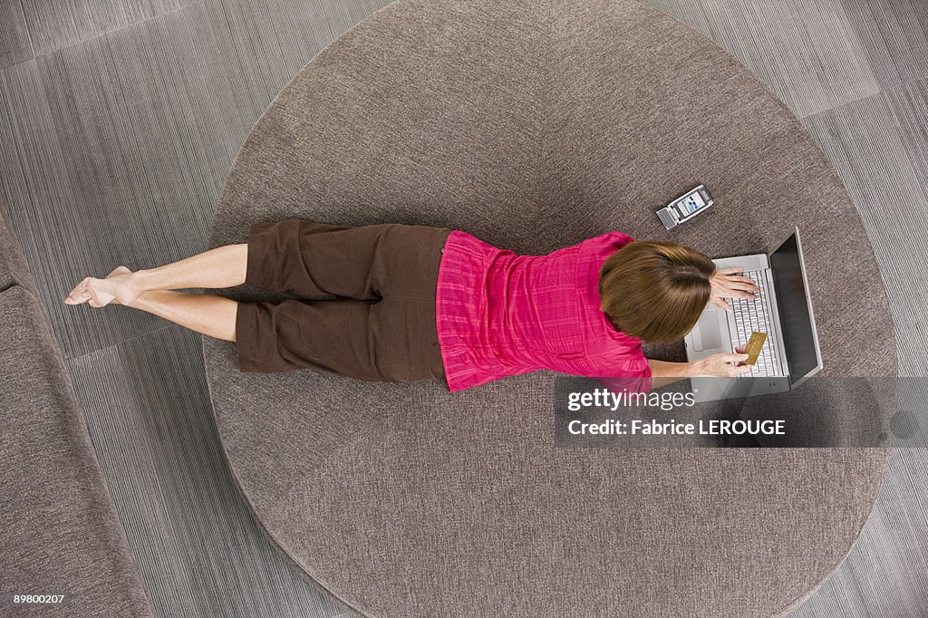 Woman holding a credit card and working on a laptop