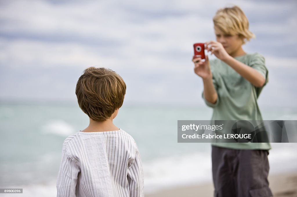 Boy taking his brother's picture with a digital camera