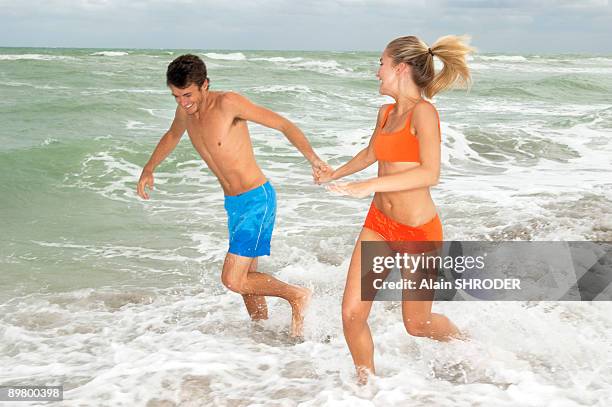 couple running in water on the beach - ankle deep in water fotografías e imágenes de stock