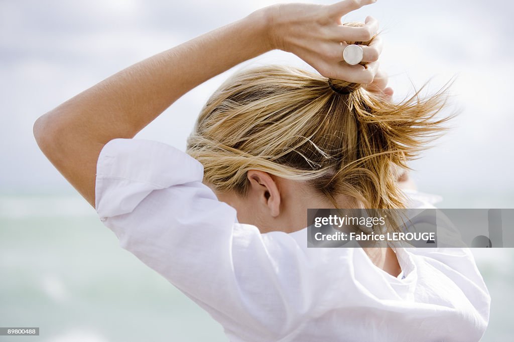 Woman setting hair in ponytail