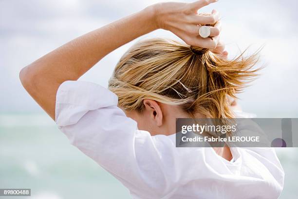woman setting hair in ponytail - cabello recogido fotografías e imágenes de stock