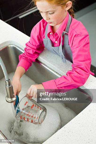 high angle view of a girl washing a measuring jug at a sink - water in measuring cup stock pictures, royalty-free photos & images