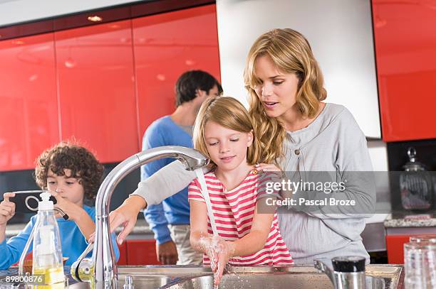 woman washing hands of her daughter in the kitchen - couples showering 個照片及圖片檔