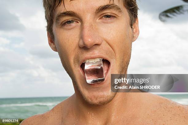 portrait of a man holding ice cube in his mouth - frost bite stock-fotos und bilder