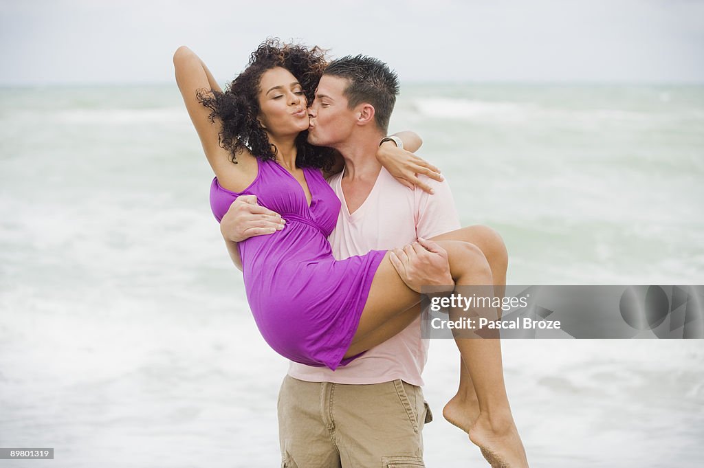 Man carrying and kissing a woman on the beach