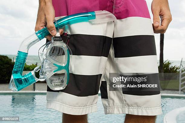 mid section view of a man holding a scuba mask at the poolside - zwembroek stockfoto's en -beelden