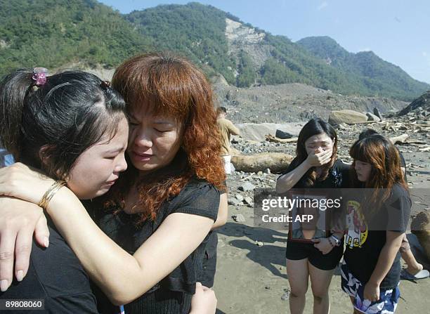 Women carrying portraits of loved ones comfort each other in the devastated village of Hsiaolin, Kaohsiung county, southern Taiwan, on August 15,...